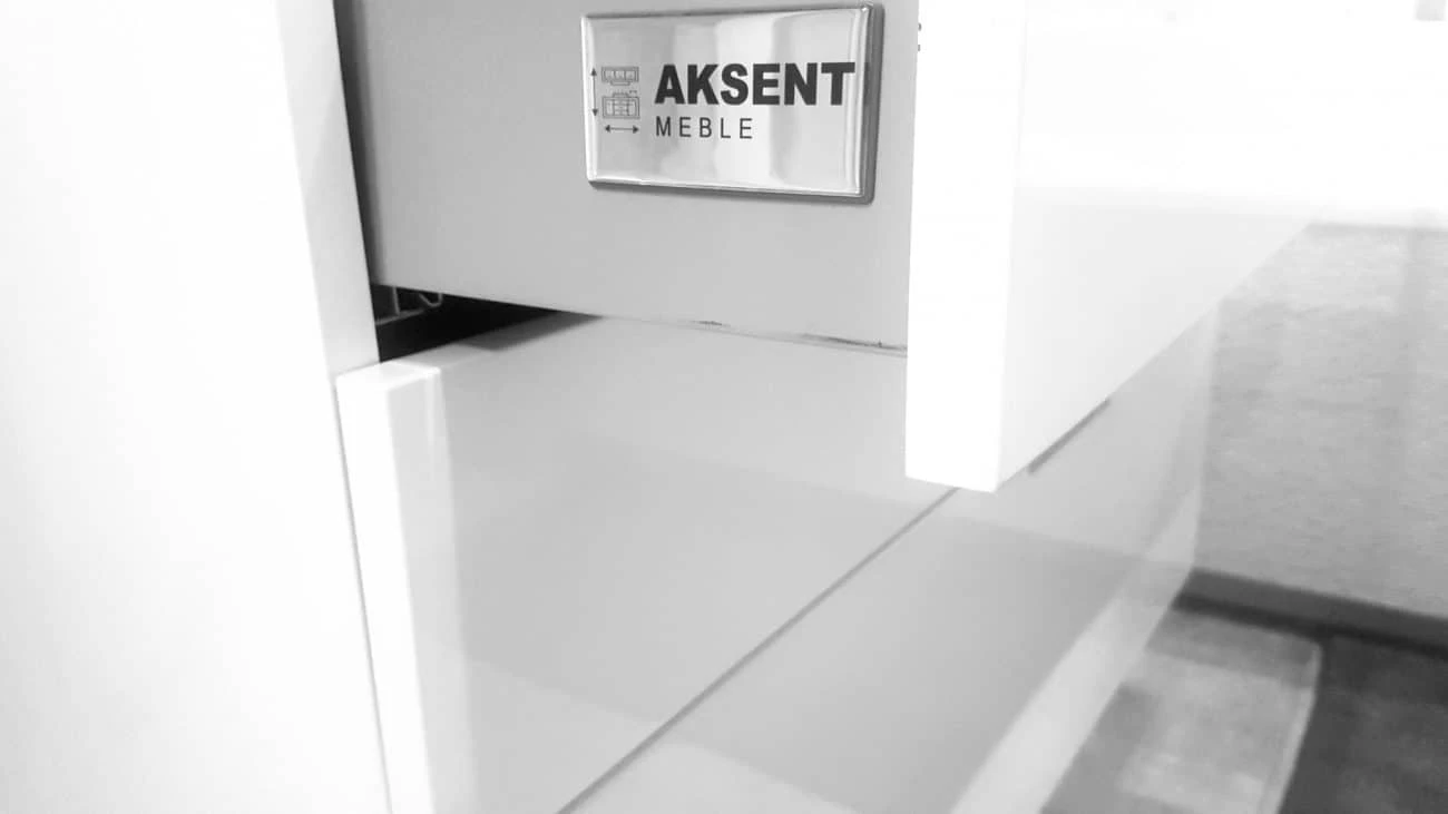 przyklejona na meble naklejka srebrna wypukła z logo Aksent