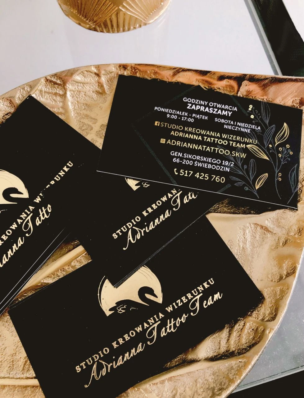 wizytówki ze złoconym logo Studio Kreowania wizerunku Adrianna Tattoo Team