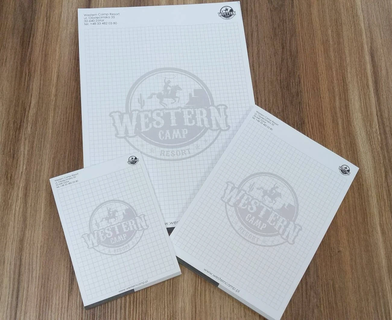 zdjęcie leżących na stole notesów reklamowych z logo Western Camp Resort