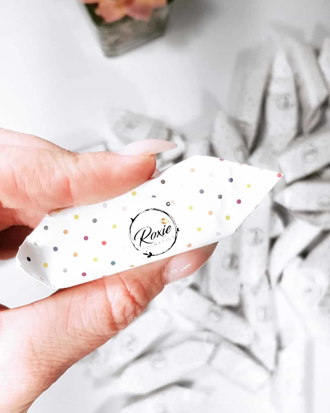 krówki reklamowe trzymane w ręku z logo Roxie cosmetics