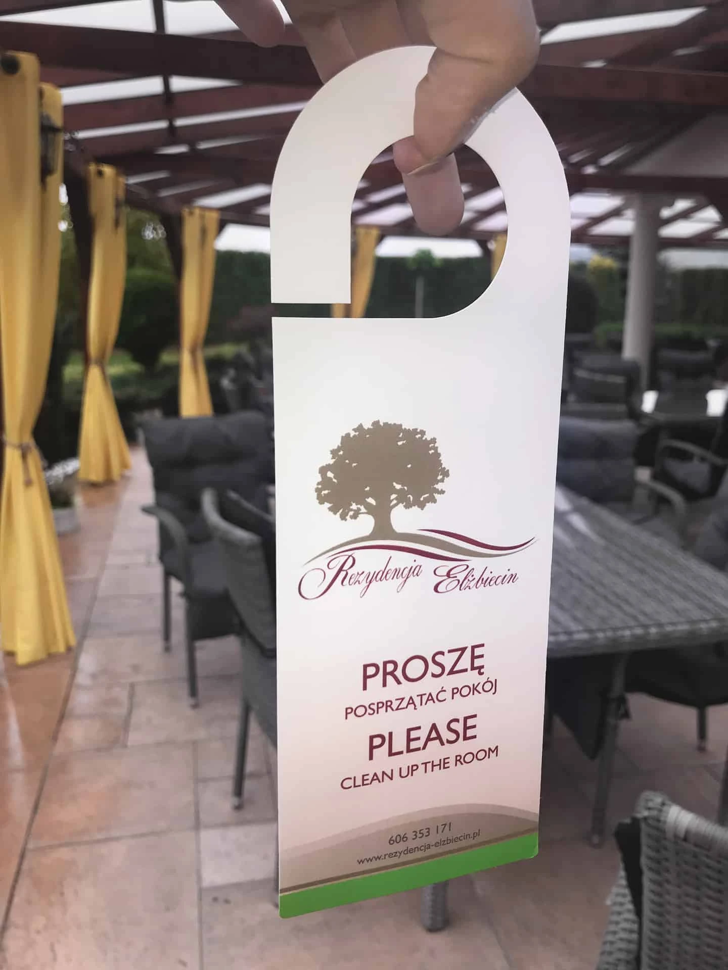 zdjęcie zawieszek na klamki z logo "Rezydencja Elżbiecin" trzymane w ręku
