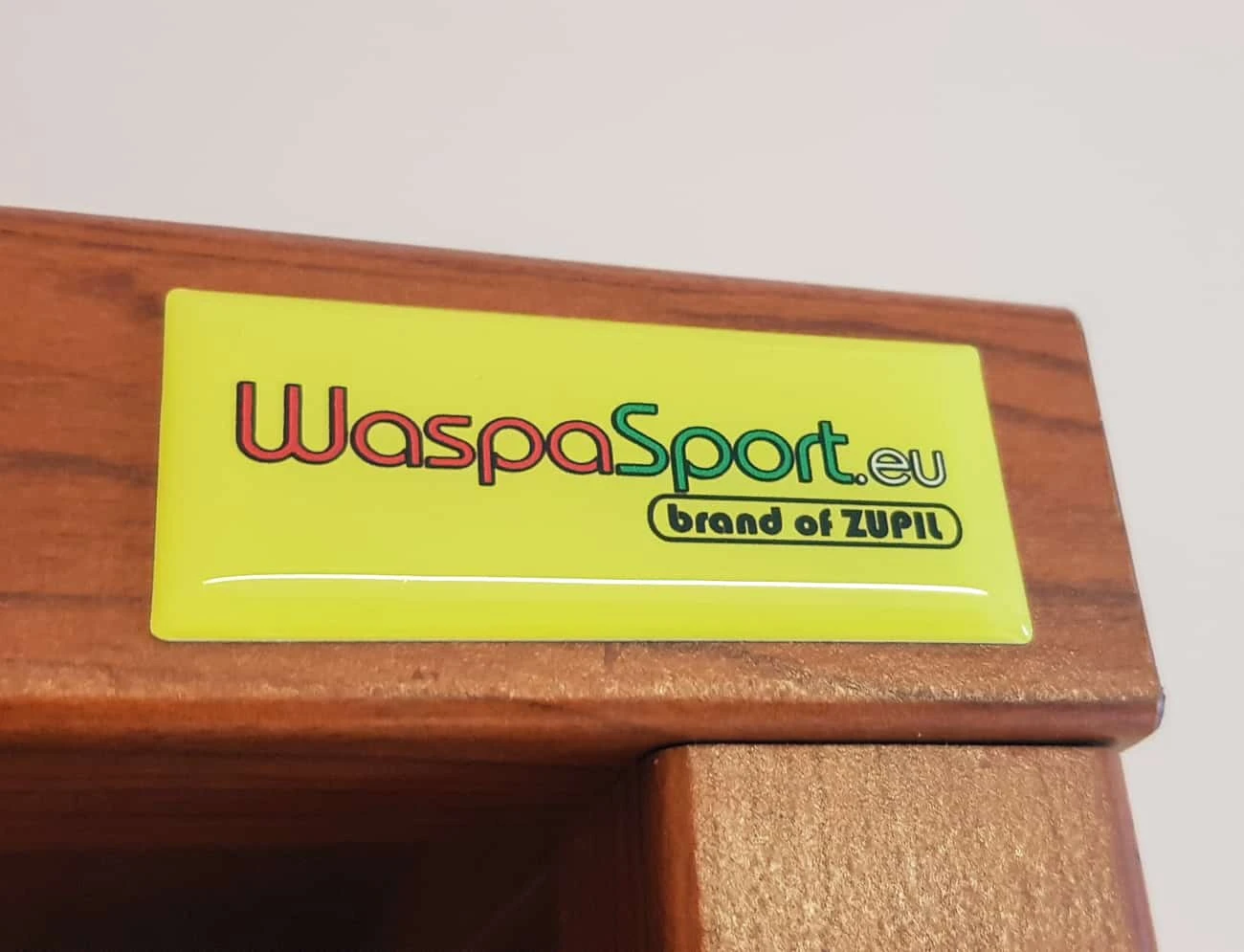 żółta naklejka przyklejona z powłoką żywiczną przyklejona na meblu. naklejka z nadrukiem WaspaSport.eu